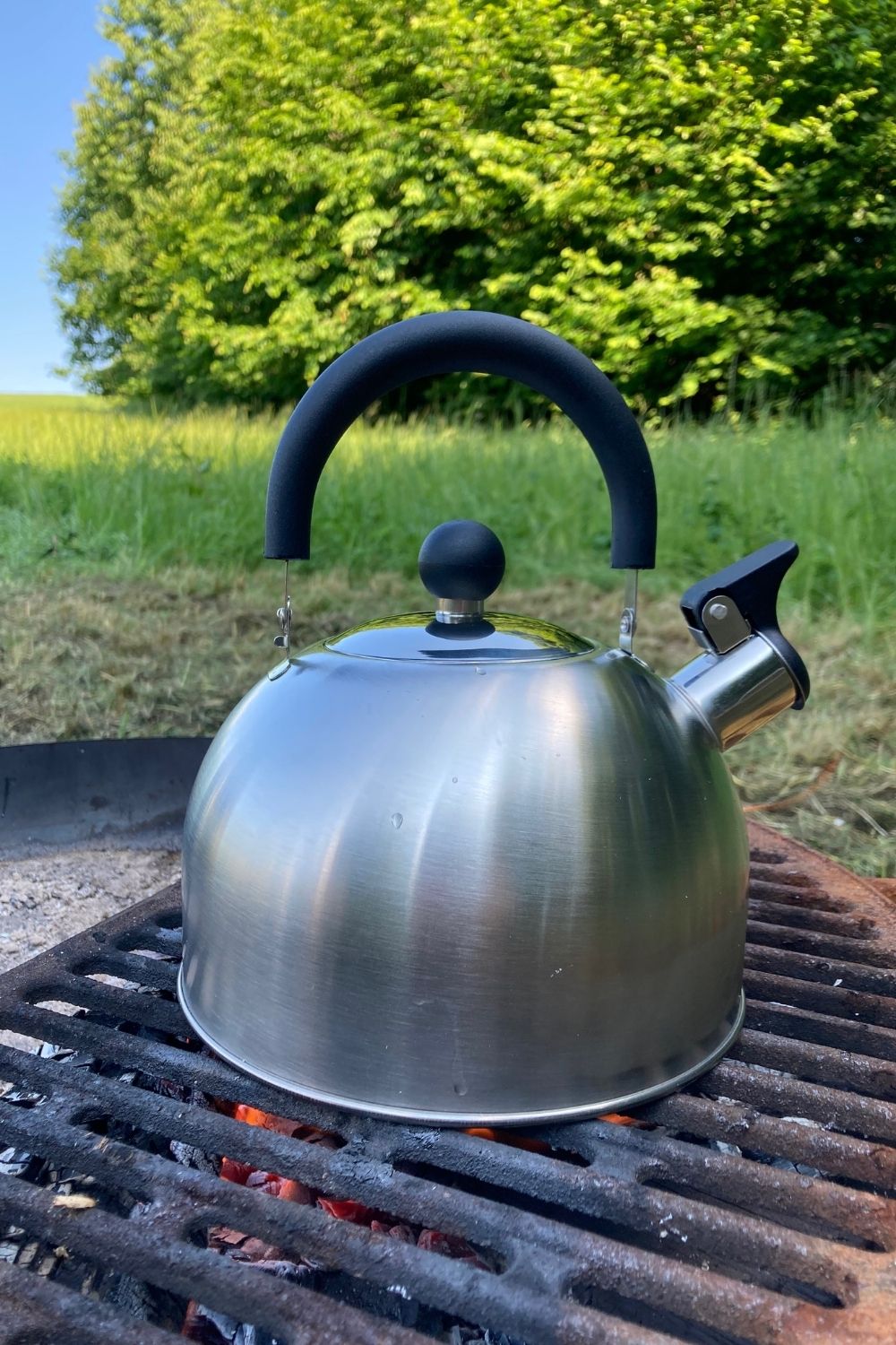 Metal kettle heating over a small campfire during a slow outdoor morning